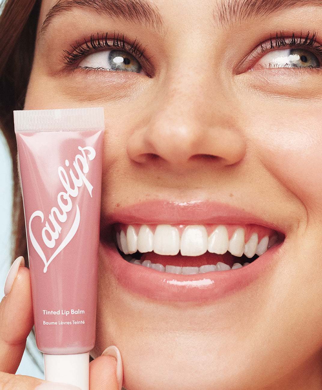 Model applying lanolips tinted lip balm in perfectly nude shade.