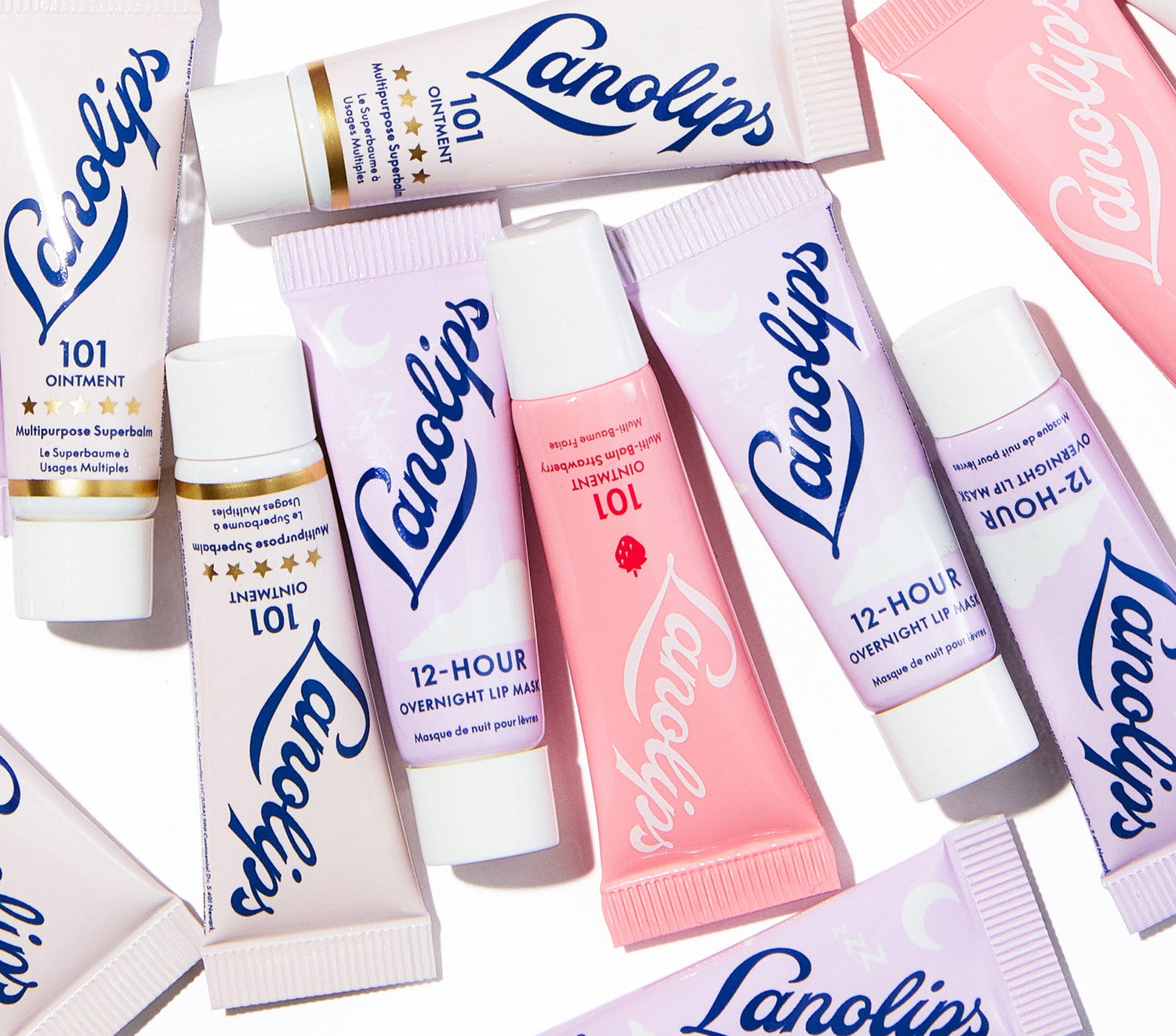 A flat lay of Lanolips Day & Night Lip Minis, featuring mini tubes of 101 Ointment Strawberry, Original 101 Ointment, and the 12 Hour Overnight Lip Mask. Voted 'The World’s Best Lip Balms', each balm delivers long-lasting hydration using ultra-pure Aussie lanolin. Strawberry 101 is enriched with real fruit extract and vitamin E, the Original 101 offers 100% natural protection from dryness, and the Overnight Lip Mask deeply hydrates lips while you sleep.