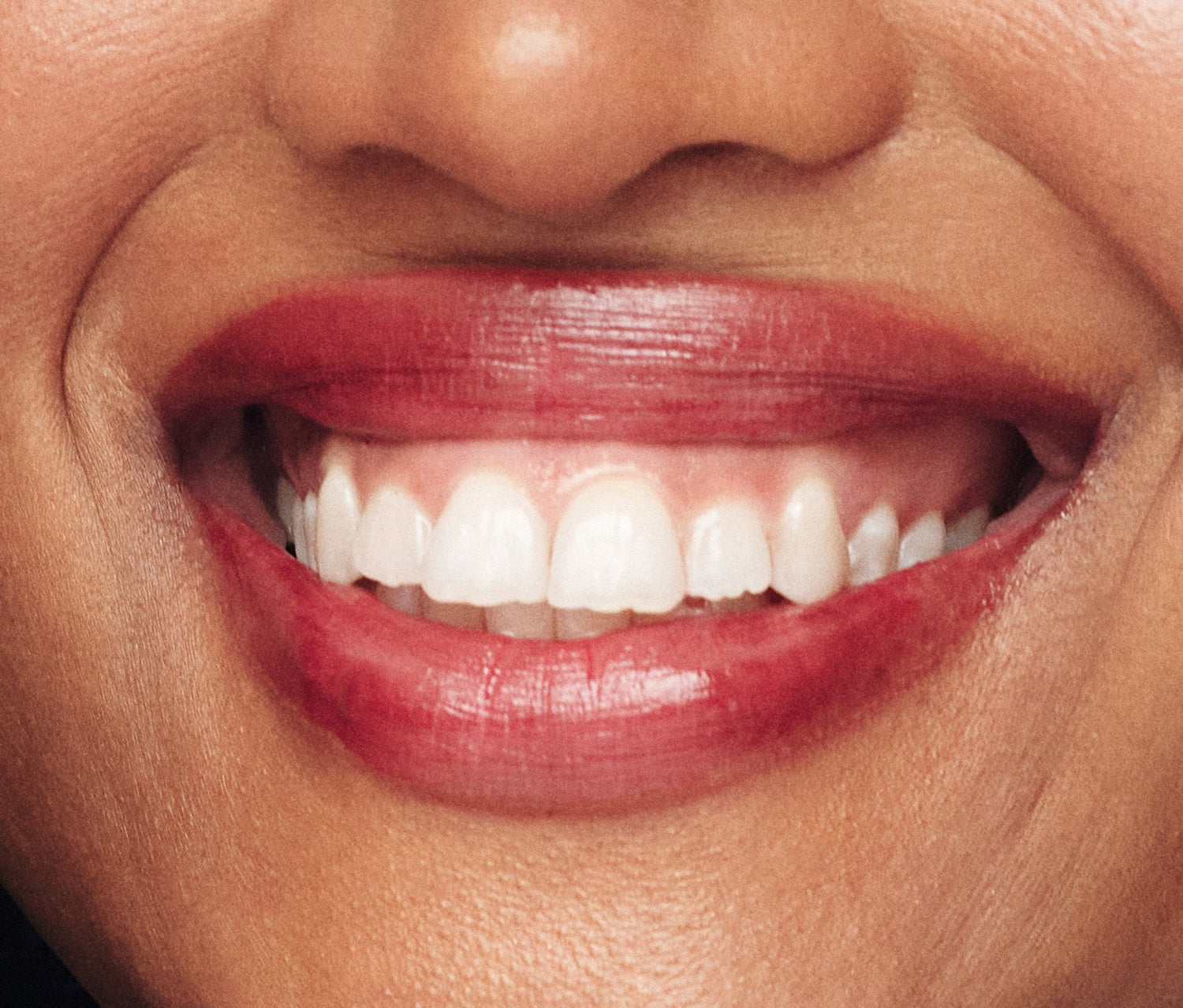 Close up shot of model wearing Lanolips Tinted Lip Balm in ‘Spice’, a deep plum shade that enhances her natural lip colour with a high-gloss, hydrated finish. Infused with ultra-nourishing lanolin, vitamin E, and shea butter, this balm provides lasting moisture and a smooth, non-sticky feel. Designed to soften and condition lips, this cult-favourite balm blends skincare and beauty in one, delivering hydration with a hint of tint.