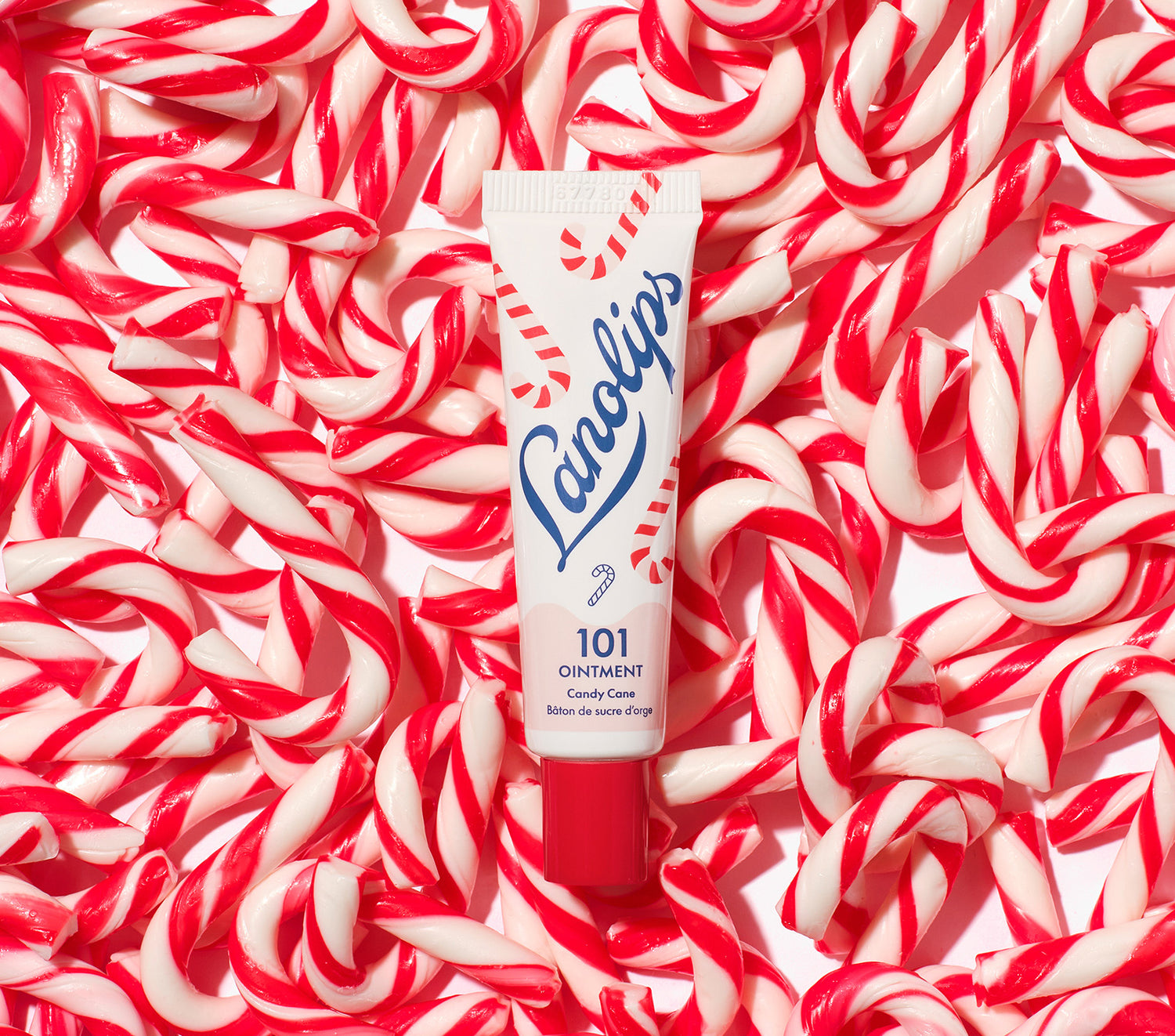 Lanolips 101 Ointment Multi-Balm Candy Cane tube surrounded by red and white candy canes. Limited edition festive flavors.