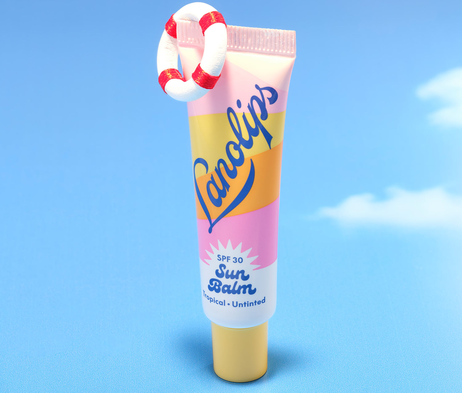 Lanolips Sun Balm SPF 30 Tropical lip balm stands upright against a blue sky, adorned with a mini lifebuoy - bright, bold, and ready for summer lips.