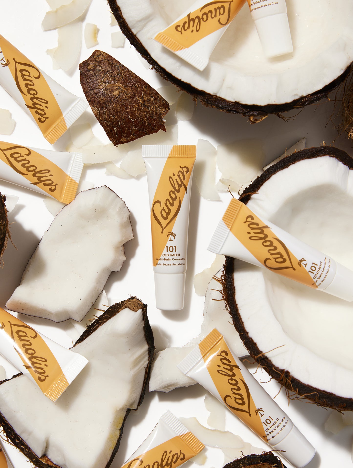 Mini sized tubes of the Lanolips 101 Ointment Multi-Balm Coconutter lip balm tubes with coconut pieces on a white background.
