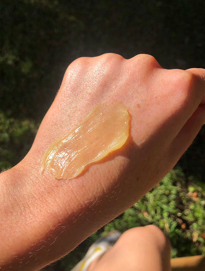 Lanolips golden dry skin miracle salve on skin on a models hand.