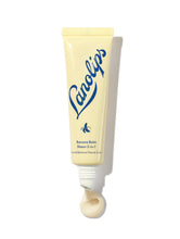  Lanolips Banana Balm Sheen 3-in-1 in a soft yellow squeezable tube with a white cap. The packaging features the Lanolips logo in bold blue lettering and a small banana icon, highlighting its creamy, nourishing formula. A swirl of the balm is visible at the opening, showcasing its rich texture and subtle pearlescent sheen. This hydrating lip balm is infused with lanolin and banana extract, designed to soften, condition, and add a natural glow to dry lips. | Load image into Gallery viewer,  Lanolips Banana Balm Sheen 3-in-1 in a soft yellow squeezable tube with a white cap. The packaging features the Lanolips logo in bold blue lettering and a small banana icon, highlighting its creamy, nourishing formula. A swirl of the balm is visible at the opening, showcasing its rich texture and subtle pearlescent sheen. This hydrating lip balm is infused with lanolin and banana extract, designed to soften, condition, and add a natural glow to dry lips.
