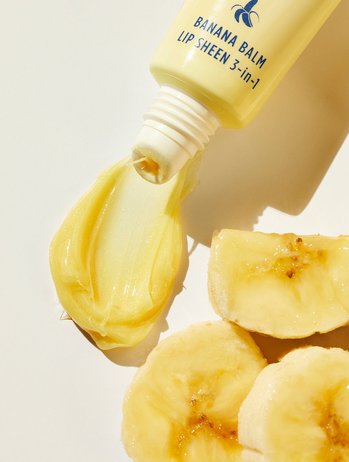 Lanolips Banana Balm Lip Sheen 3-in-1 tube squeezed with banana pieces close up.