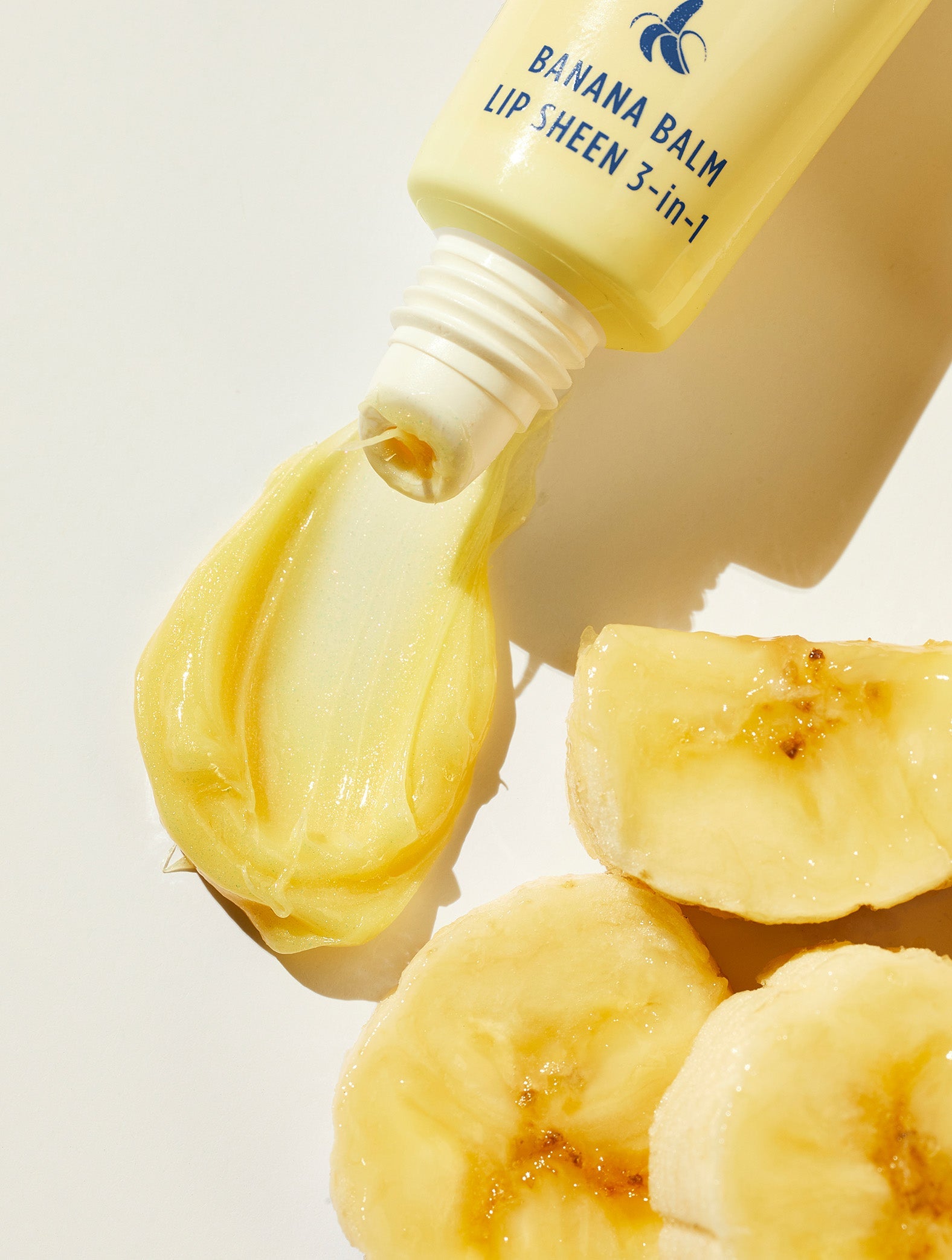 Lanolips Banana Balm Lip Sheen 3-in-1 tube squeezed with banana pieces close up.