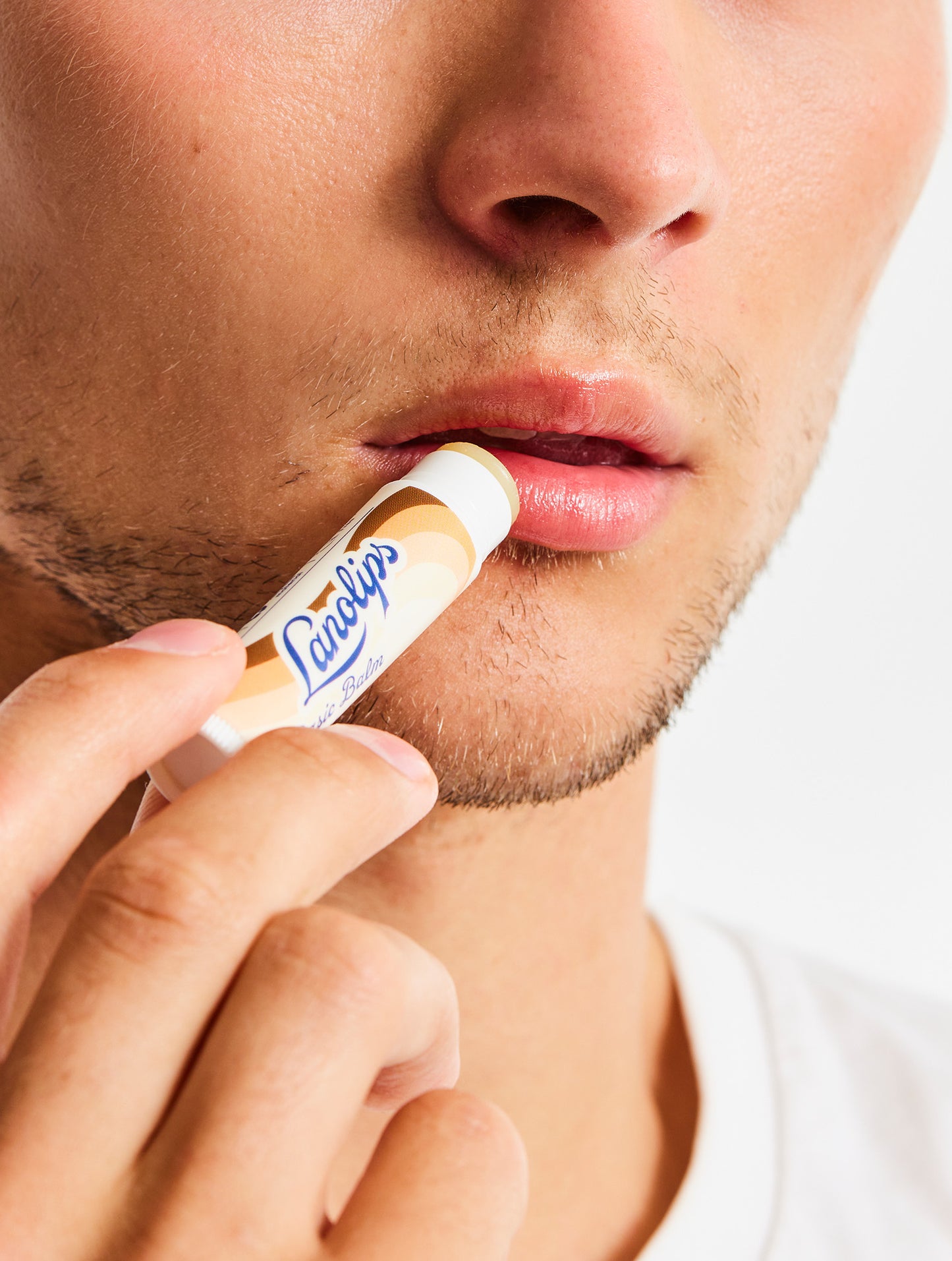 Model applying a Lanolips Basic Balm Coconutter lip balm to their lips.