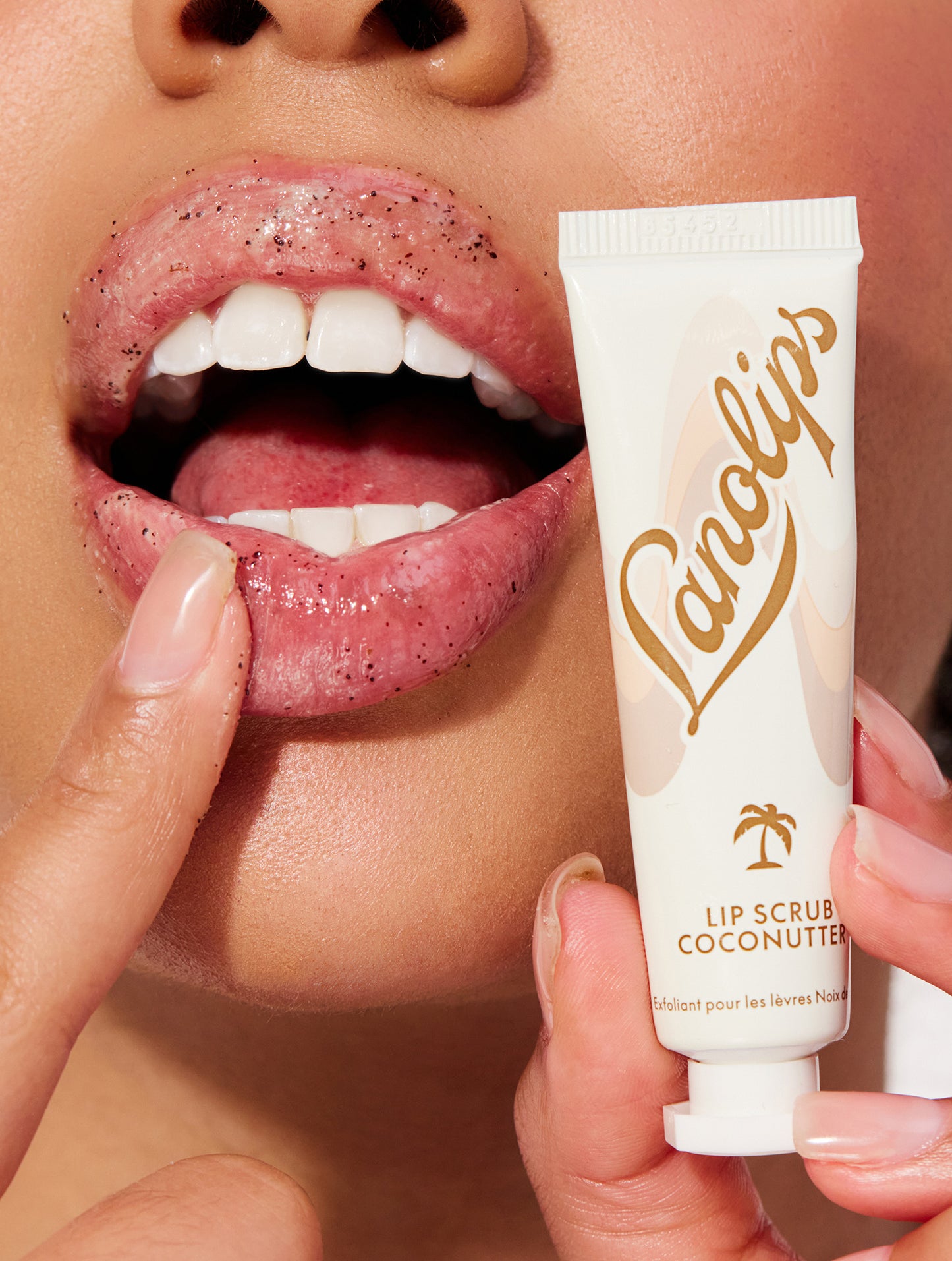 Model applying lanolips lip scrub in coconutter to her lips.