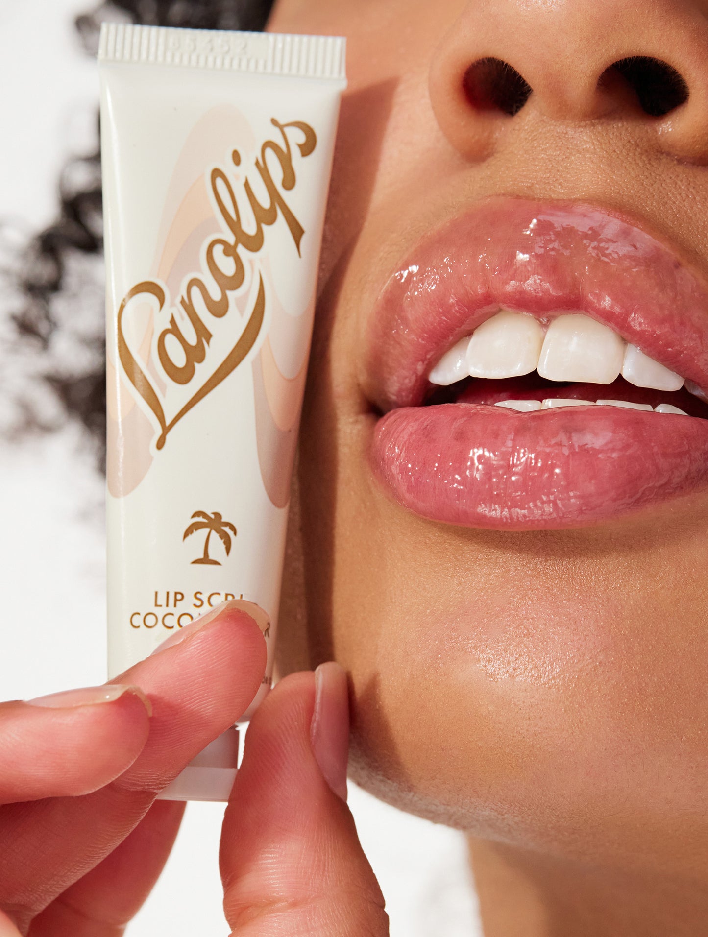 Model holding lanolips lip scrub in coconutter in her hand.