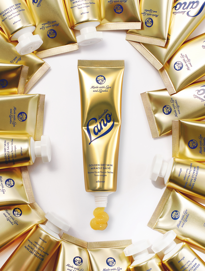 Product Shot of Lanolips Golden Dry Skin Miracle Salve 60g tube, surrounded with multiple closed tubes . An ultra-hydrating, multi-purpose formula designed to deeply nourish and repair very dry skin, hands, and rough patches.