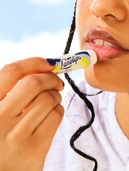 Person applying Lanolips Basic Balm Original Vanilla lip balm to their lips with a clear background